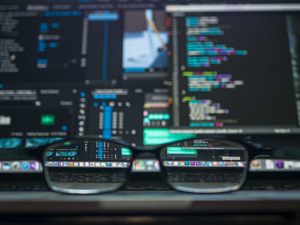 Glasses on a desk with computer code in the background